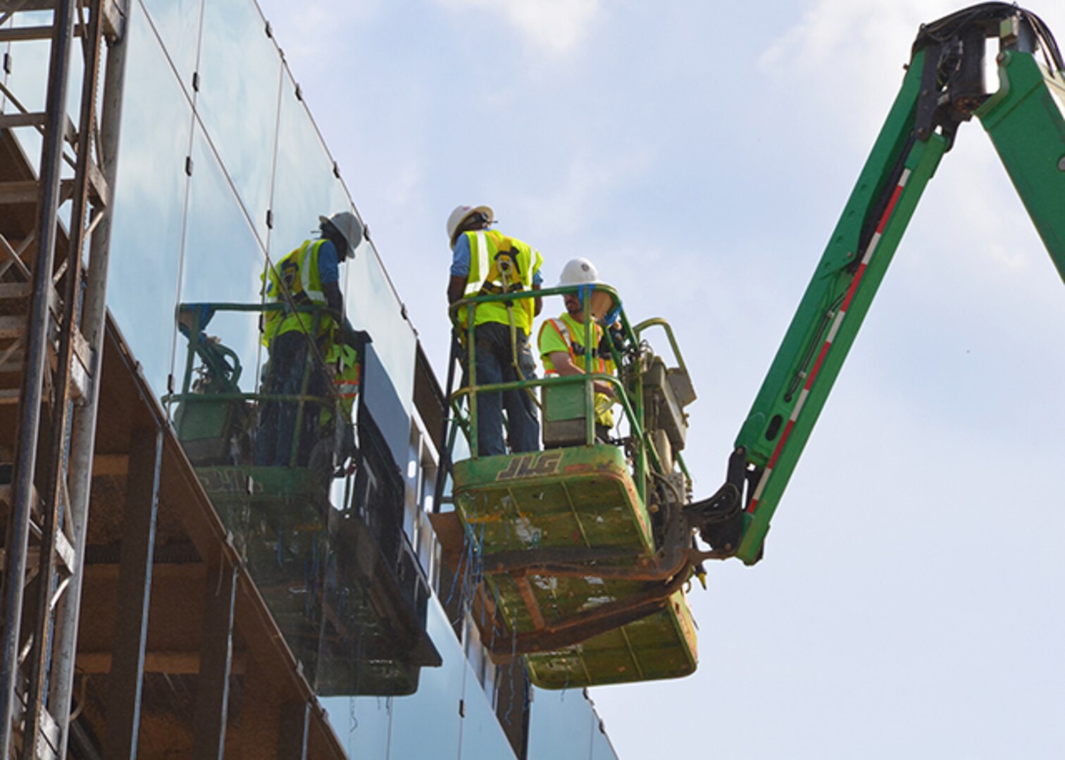 Construction workers install glass as part of a curtain wall system to the front of the new DLA Aviation Operations Center April 12, 2017.  The curtain wall system is a non-structural covering on the building to keep weather out and occupants in.  The wall made of lightweight material reduces construction costs and allows natural light to penetrate deeper within the building.