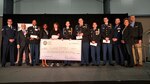 Five students from Alamo Heights Army JROTC pose on stage with their mentors as well as civic and cyber industry officials as they accept awarded scholarship money from the Armed Forces Communications and Electronics Association (AFCEA) during the Mayor’s Cyber Cup luncheon April 6, 2017 in San Antonio, Texas. The cadets were one of the five Alamo Heights cyber teams that competed in the CyberPatriot Cyber Defense Competition, placing fourth overall in their division. Staff Sgt. William Jones (far left), 92nd Cyberspace Operations Center, led the team of Airmen that mentored the students. (Courtesy photo)
