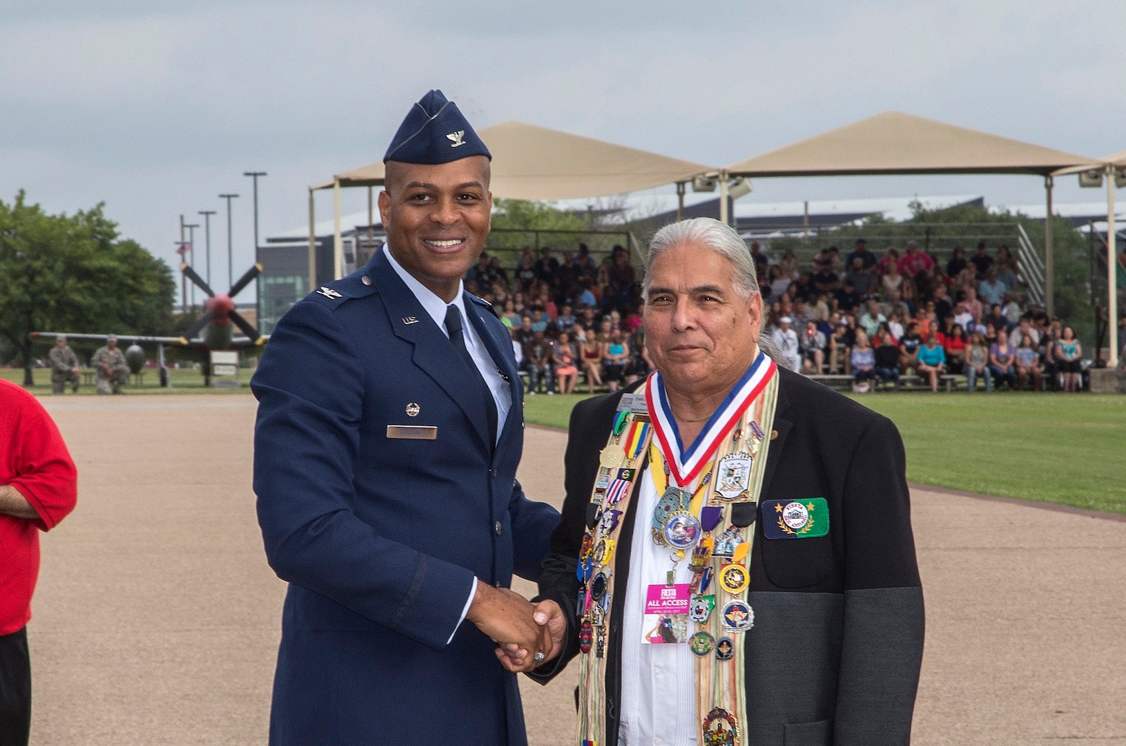 Col. Roy Collins, 37th Training Wing commander, give San Antonio Fiesta Commission president Erwin De Luna a gift during the Air Force Basic Military Training Fiesta graduation Parade April 21, 2017, at Joint Base San Antonio-Lackland, Texas. Each year, members of the Fiesta Royalty Court conduct the Royal Review of a BMT graduation during Fiesta San Antonio, a 10-day celebration of military history to honor the life and memory of the members who died in the Battle of the Alamo and the Battle of San Jacinto. Servicemembers from around JBSA participate in Fiesta San Antonio activities representing the progression of the United States military. (U.S. Air Force photo by Johnny Saldivar)