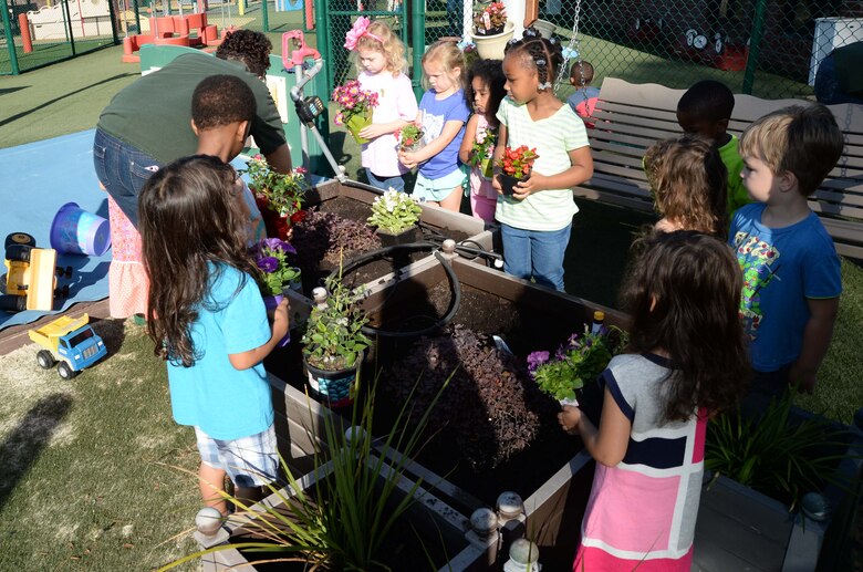 Students and personnel at the Child Development Center, aboard Marine Corps Logistics Base Albany, plant flowers as well fruit-bearing bushes in observance of the 2017 Earth Day, here, April 21. The annual event teaches young scholars about the importance of preserving the environment through planting and caring for the foliage, which they have planted in containers situated around the perimeter of the children’s playground.