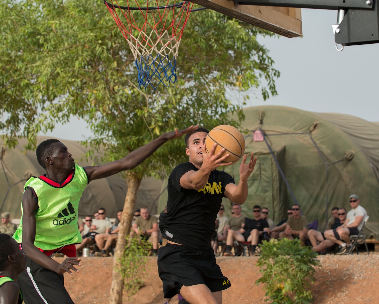 Army Pfc. Darian Hampton of Task Force Toccoa sneaks past a Cameroonian defender for a layup during a basketball game with American and Cameroonian service members in Garoua, Cameroon, April 21, 2017. The task force, which is supporting Cameroon's efforts against Boko Haram, decided to hold the game to help build better cohesion between American and Cameroonian military members. DoD photo by Sean Kimmons