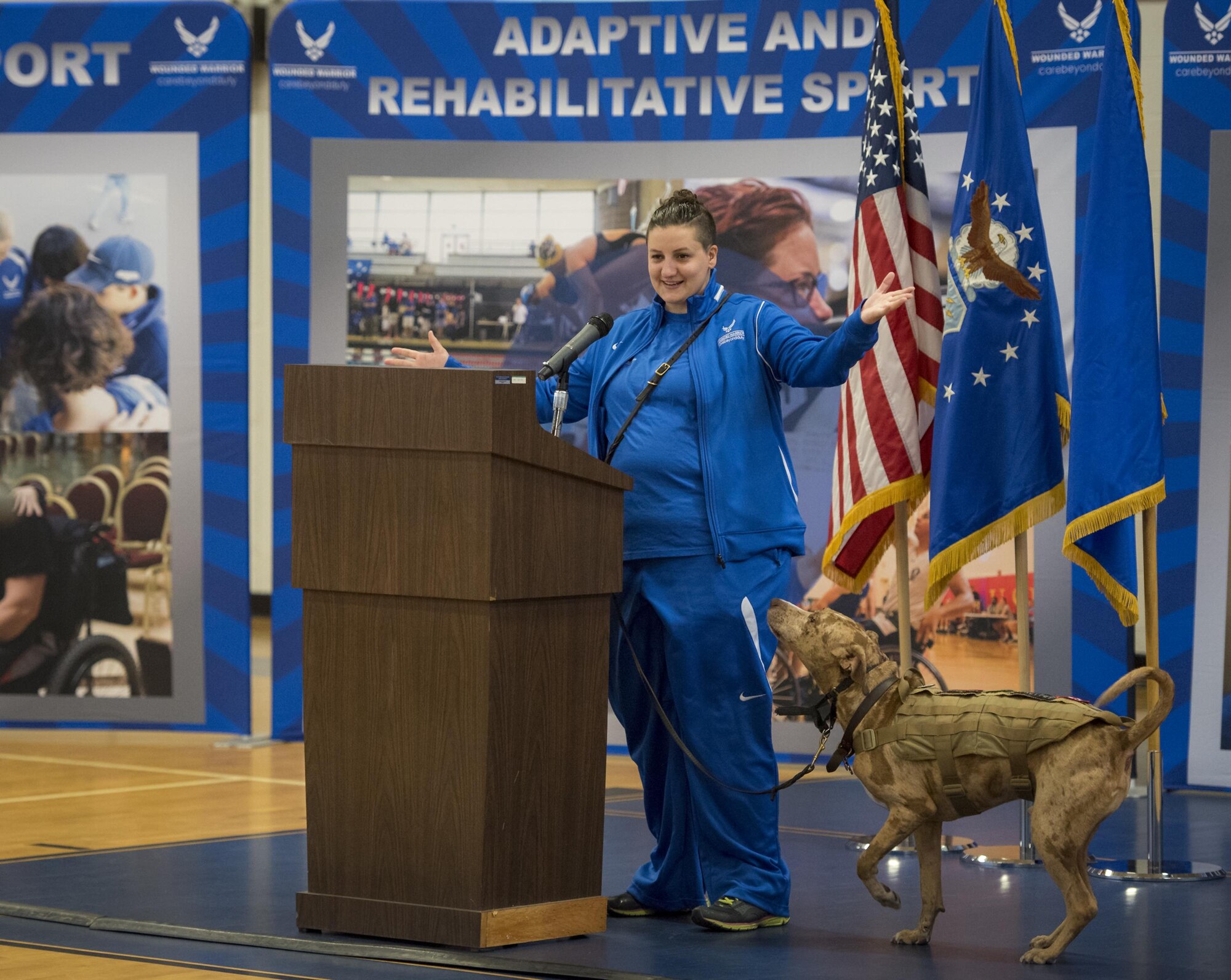 Hanna Stulberg, with her service dog, Valhalla, welcome the Warrior CARE attendees and Warrior Games athletes to the opening ceremony of the two events April 24 at Eglin Air Force Base, Fla. The ceremony kicked off a week-long rehabilitative wounded warrior camp as well as a training session for the Air Force Warrior Games athletes. (U.S. Air Force photo/Samuel King Jr.)