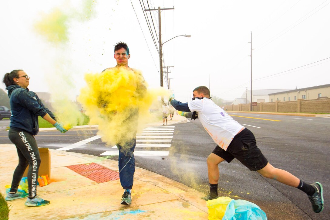 Course volunteers throw colored powder on 5k runners during the Sexual Assault Awareness Month Color Run April 21, 2017, at Dover Air Force Base, Del. Volunteers waited at five different color stations to cover passing runners in brightly colored powder. (U.S. Air Force photo by Mauricio Campino)