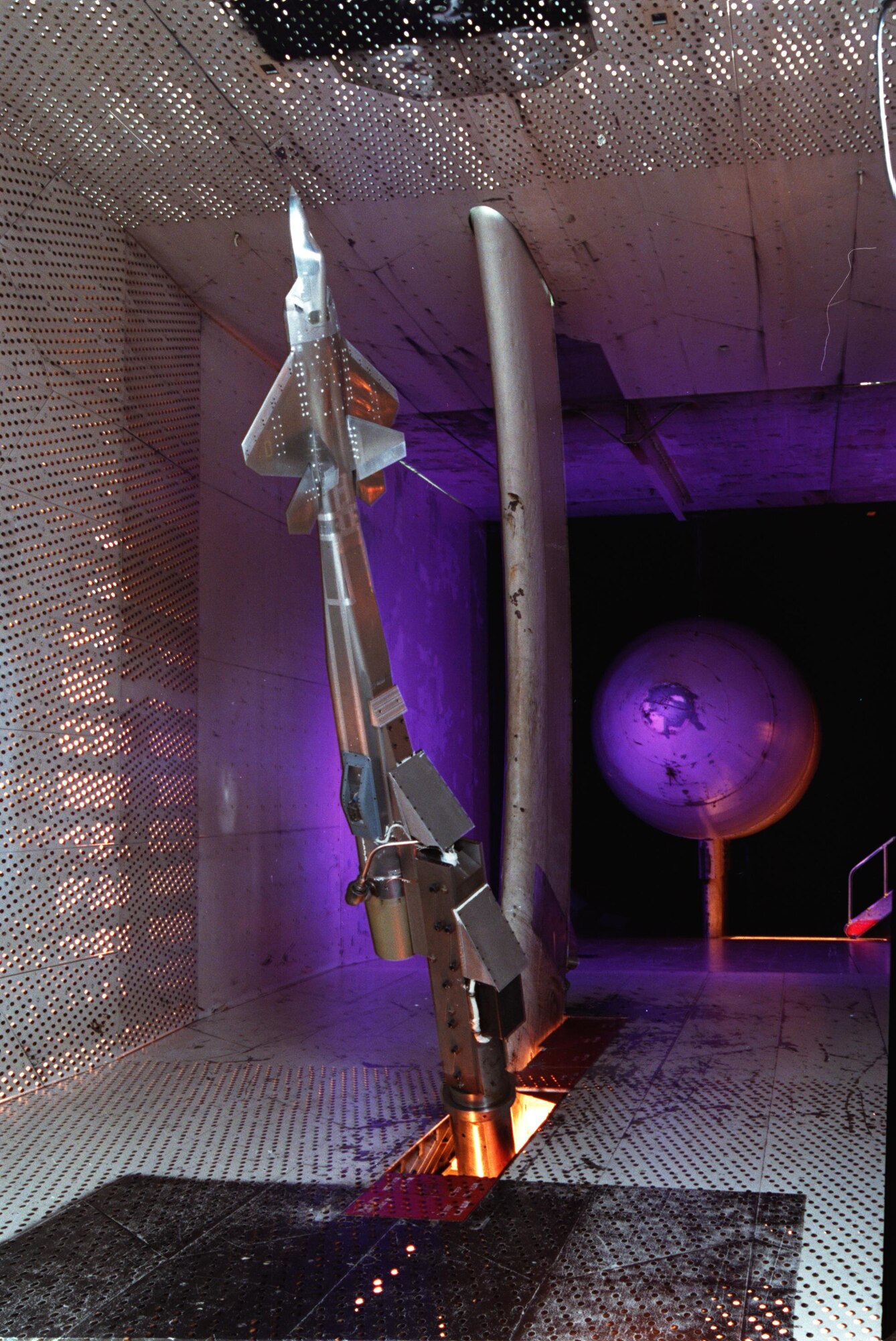 An F-22A aircraft model is maneuvered to a very high angle of attack during wind tunnel testing in 16T in 1995. This test helped to define performance and aircraft stability and control. (AEDC photo)