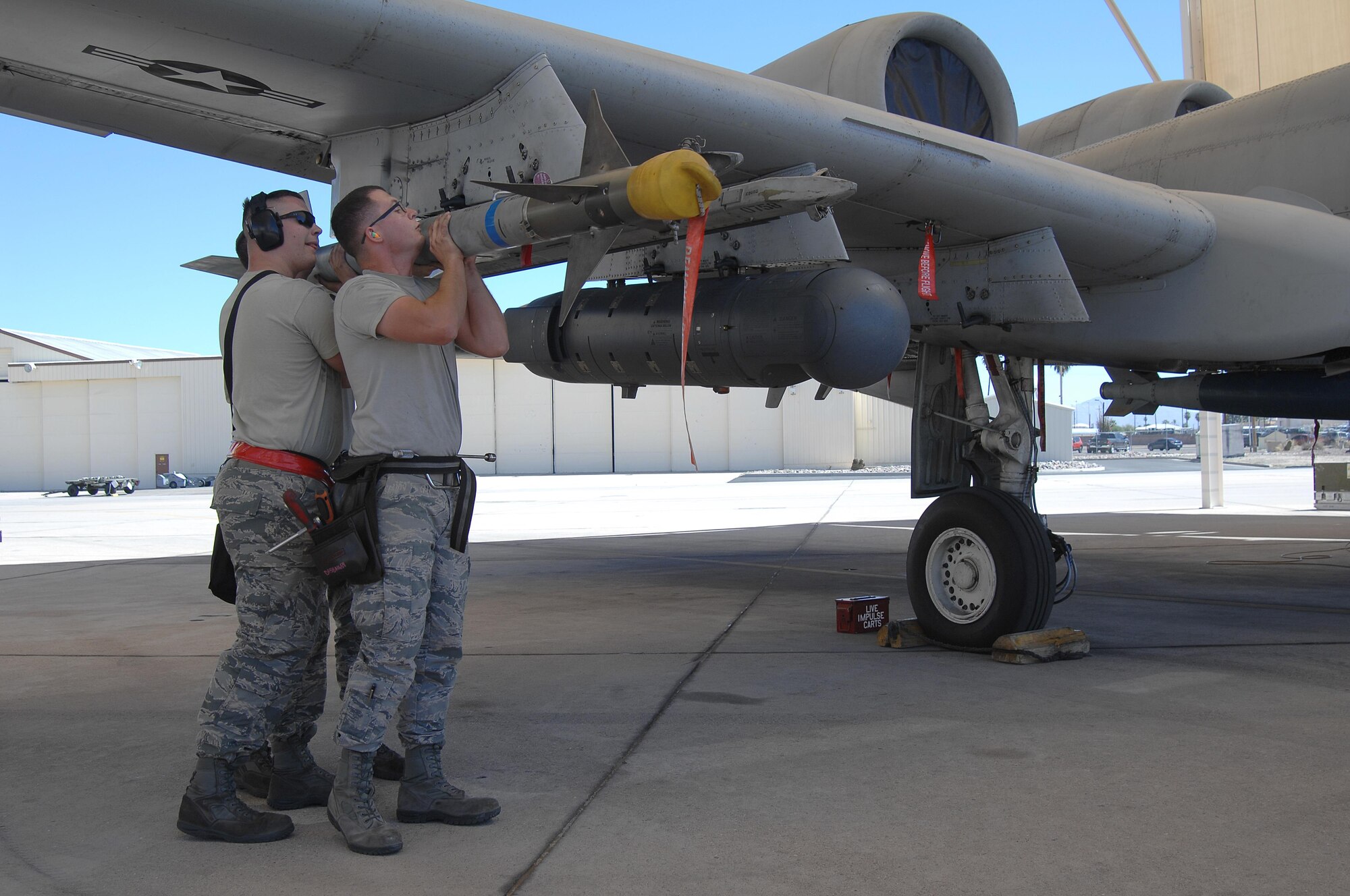 U.S. Air Force Staff Sgt. Christopher Ouellet, Airman 1st Class Erik Wiley and Zachary Rhodes, 357th Aircraft Maintenance Unit weapons load crew team members, load an AIM-9 Sidewinder missile onto an A-10C Thunderbolt II during a load crew of the quarter competition at Davis-Monthan Air Force Base, Ariz., April 21, 2017. The load crews were required to complete their assigned tasks in accordance with their technical orders in the least amount of time possible. (U.S. Air Force photo by Airman 1st Class Frankie D. Moore)