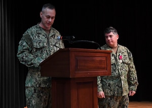 Capt. Chase Patrick, left, reads his orders during a change of command ceremony for Destroyer Squadron 50/Task Force 55 onboard Naval Support Activity Bahrain. DESRON 50 is the permanent afloat arm of the U.S. 5th Fleet and conducts theater operations in support of national and coalition security as well as partnership, strength and presence.