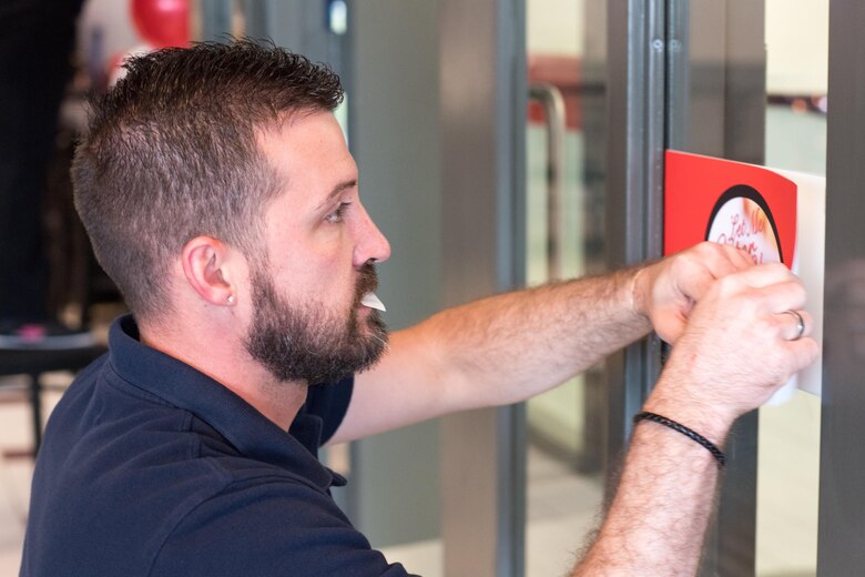 Jason Dellinger, a visual merchandiser with the Fort Bragg Exchange, attaches a grand-opening sign in a new restaurant which held its grand opening at the Airmen's Center here April 7. Open for breakfast and lunch on weekdays, the new veteran-owned restaurant operates similar to military dining facilities, offering service members and civilians convenient access to dining here at Pope. (U.S. Air Force photo/Marc Barnes)