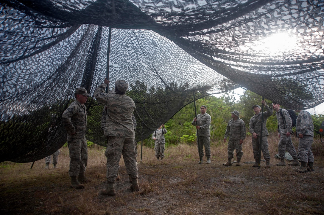 U.S. airmen set up camo netting on Kadena Air Base, Japan, April 21, 2017. The preventative aerospace medicine convention tested the capabilities of 18th Medical Group airmen on the setup requirements for deployed environments. Air Force photo by Airman 1st Class Quay Drawdy