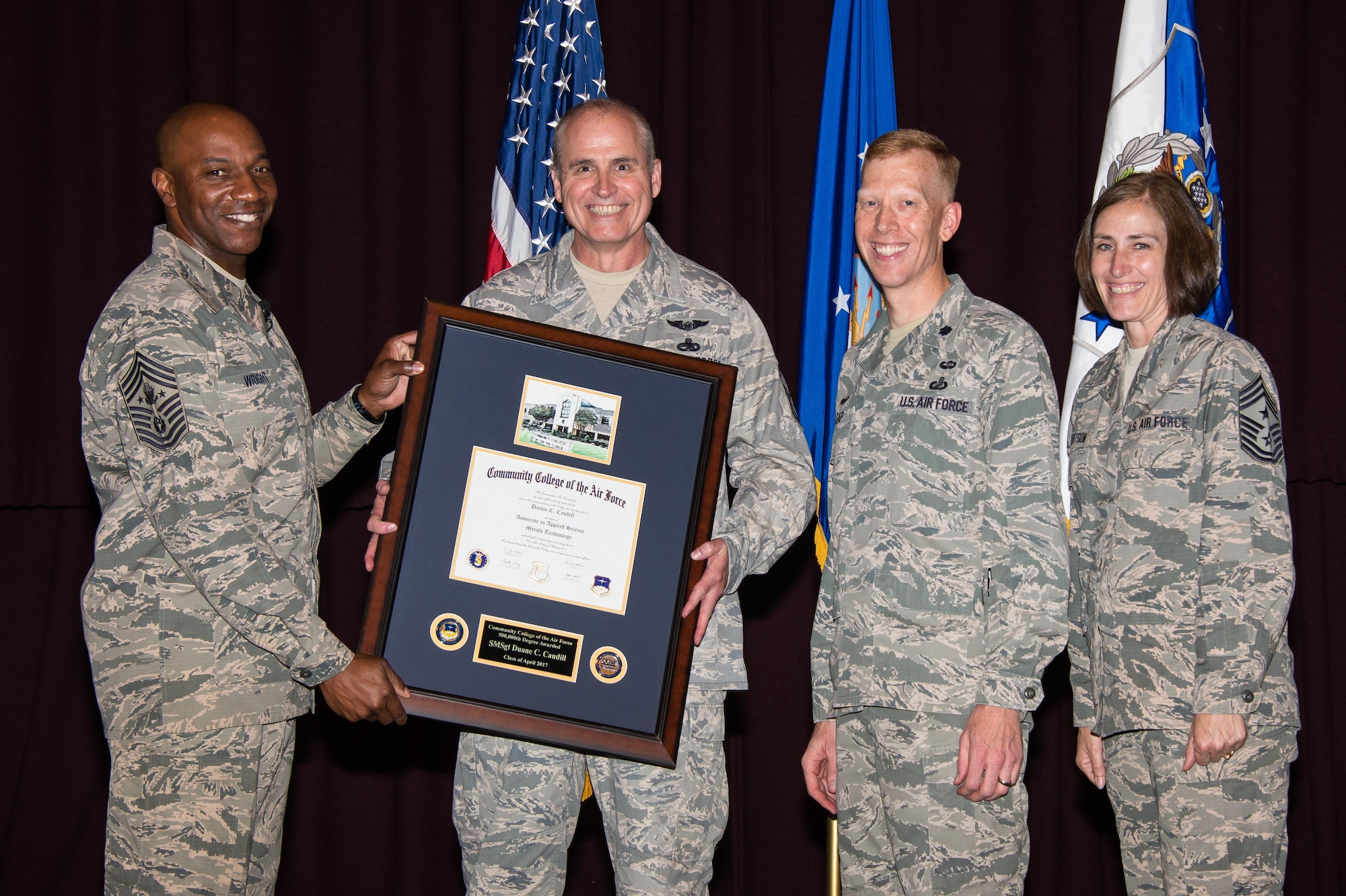 Chief Master Sgt. of the Air Force Kaleth O. Wright, presents Senior Master Sgt. Duane Caudill, 302nd Maintenance Group career advisor, with the 500,000th Community College of the Air Force degree, April 21, 2017, Maxwell Air Force Base, Ala. The Community College of the Air Force commandant, Lt. Col. Nathan J. Leap, and Chief Master Sgt. Vicki Robertson, 302 Airlift Wing Command Chief, also participated in the historic presentation. (US Air Force photo by Melanie Rodgers Cox)