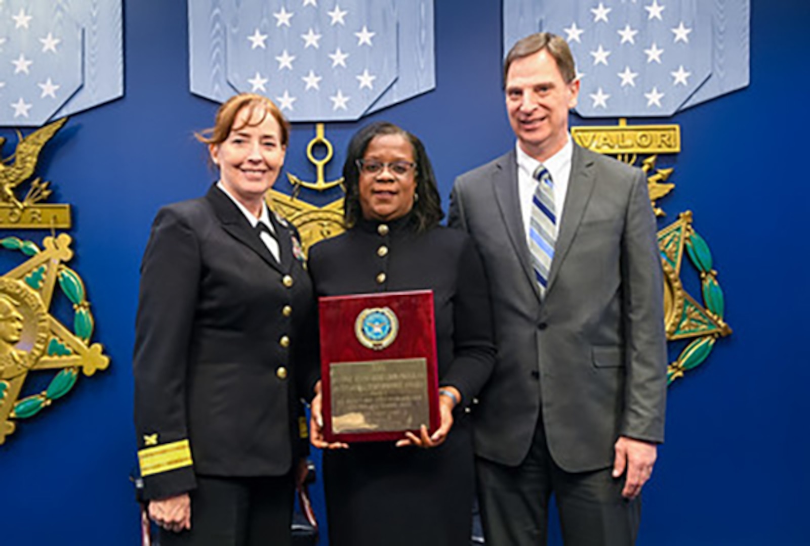 Mary McWilliams (center), DLA Land and Maritime electronics engineer, displays the Defense Standardization Program Award she received during a ceremony in Washington as she’s flanked by DLA Land and Maritime Commander, RDML Michelle Skubic (left) and Michael Radecki, Land and Maritime’s chief of electronics components on the right. (U.S. Army photo by Sgt. Alicia Brand)