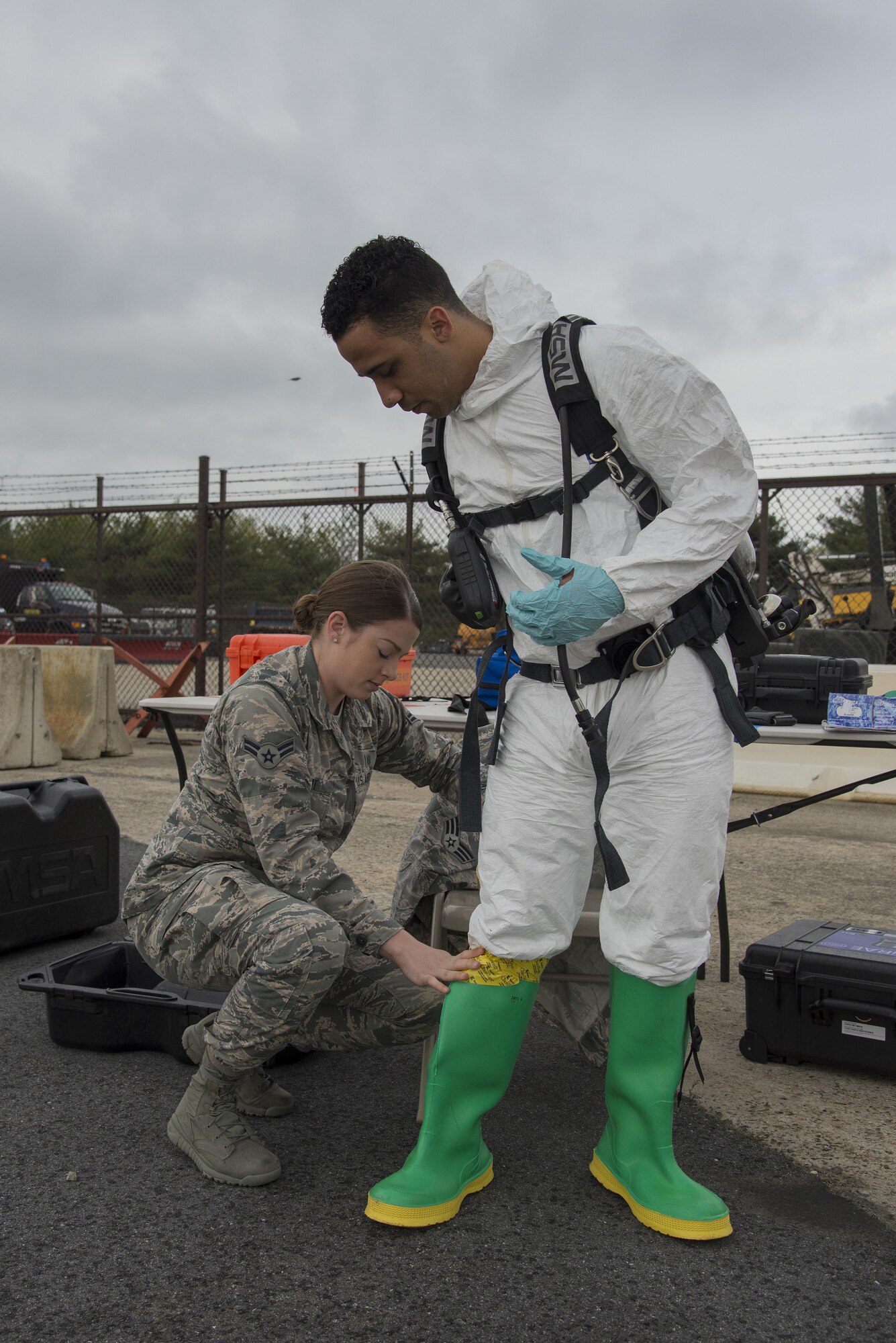 Airman 1st Class Kristina Di Maria tapes the boot of Senior Airman Jorge Rijo to his chemical suit during a fuel spill exercise April 20, 2017, at Dover Air Force Base, Del. Di Maria and Rijo, 436th Aerospace Medicine Squadron bioenvironmental engineering technicians, supported the exercise by monitoring air quality at the simulated spill site. (U.S. Air Force photo by Senior Airman Aaron J. Jenne)