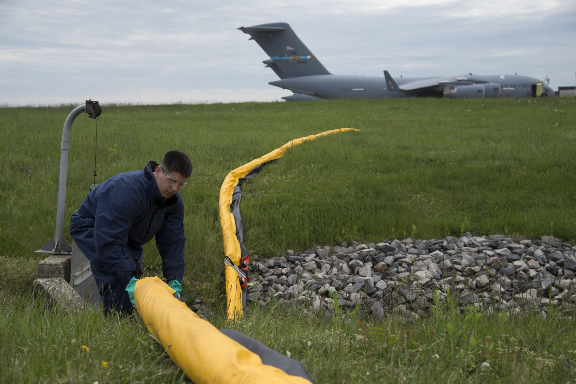Staff Sgt. Robert Simpson, 436th Civil Engineer Squadron Infrastructure and Utilities water and fuel systems maintenance technician, places a containment boom during a fuel spill exercise April 20, 2017, at a flightline drainage spill gate on Dover Air Force Base, Del. The containment boom is specially designed to work on both land and water to keep spilled fuel in a controlled area. (U.S. Air Force photo by Senior Airman Aaron J. Jenne)