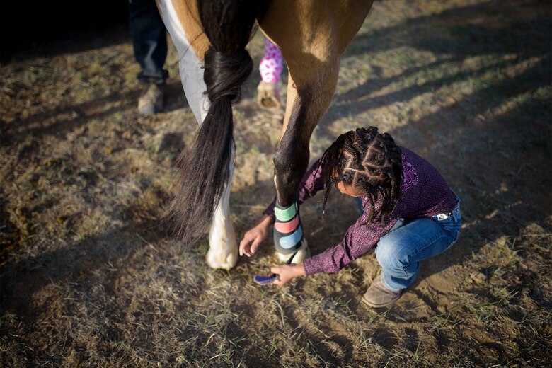 Savannah, daughter of Lt. Col. Nicole Roberts, 21st Security Forces Squadron commander, wraps the ankle of her horse, Nacho, at a barrel racing event in Loveland, Colo., April 15, 2017. Savannah began horse riding at age four. (U.S. Air Force photo by Airman 1st Class Dennis Hoffman)