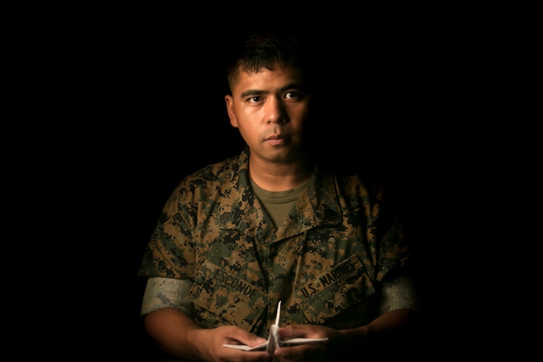 Staff Sgt. Ismael Esconde, the substance abuse control officer with Headquarters and Service Company, 3rd Battalion, 3rd Marine Regiment, holds a crane he folded at building 267 aboard Marine Corps Base Hawaii April 19, 2017. Esconde uses origami as a way to make a positive impact in his local community. (U.S. Marine Corps photo by Sgt. Brittney Vella)