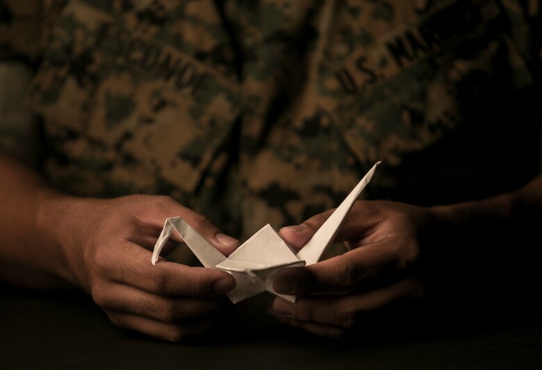 Staff Sgt. Ismael Esconde, the substance abuse control officer with Headquarters and Service Company, 3rd Battalion, 3rd Marine Regiment, holds a crane he folded at building 267 aboard Marine Corps Base Hawaii April 19, 2017. Esconde uses origami as a way to make a positive impact in his local community. (U.S. Marine Corps photo by Sgt. Brittney Vella)