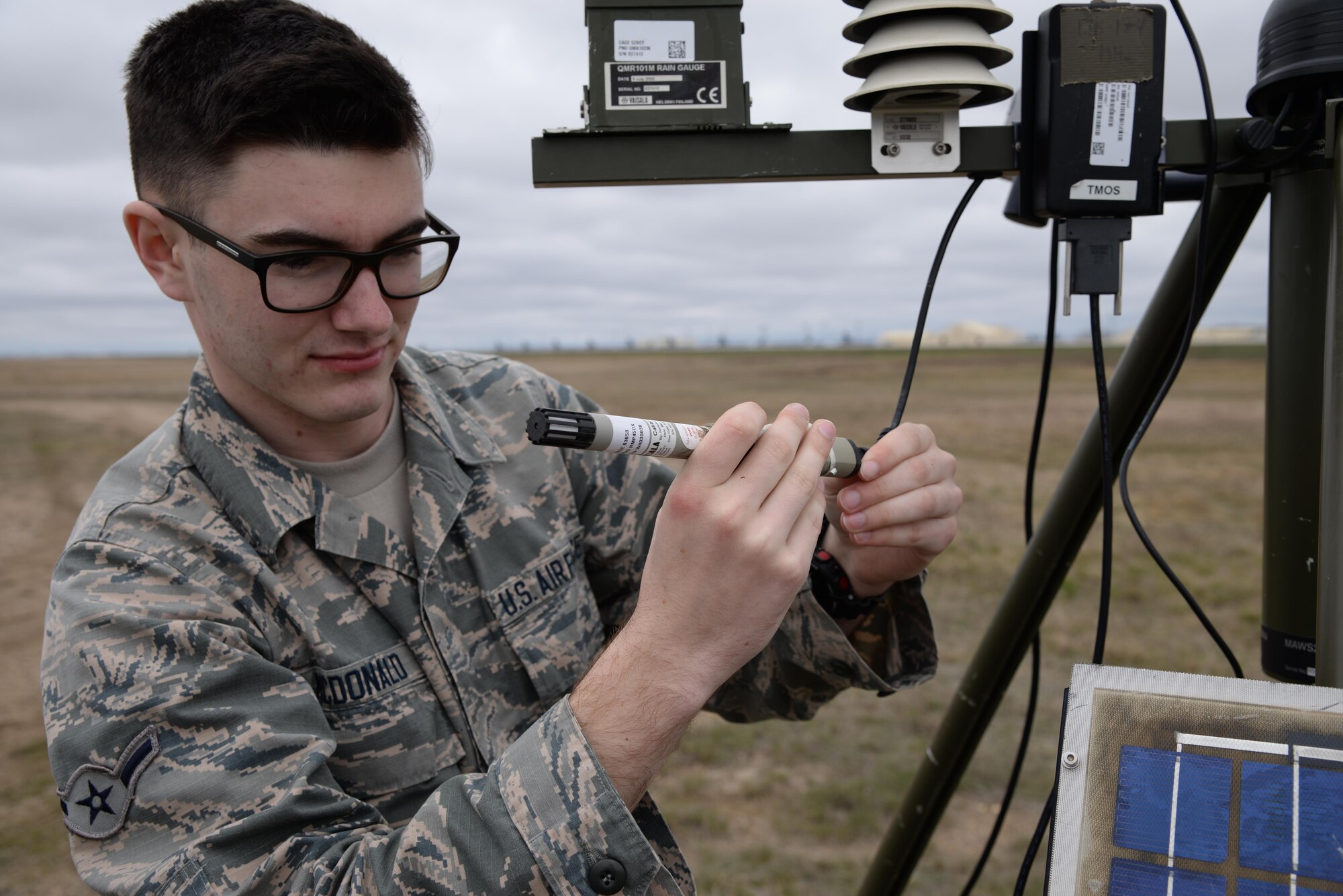 Airman Connor McDonald, 5th Operations Support Squadron weather forecaster, inspects the rain gauge on the Deployed Tactical Meteorological Observing System (TMQ-53) at Minot Air Force Base, N.D., April 18, 2017. Weather forecasters check the rain gauge every three hours and drain it out every six hours. (U.S. Air Force photos/Airman 1st Class Dillon Audit)