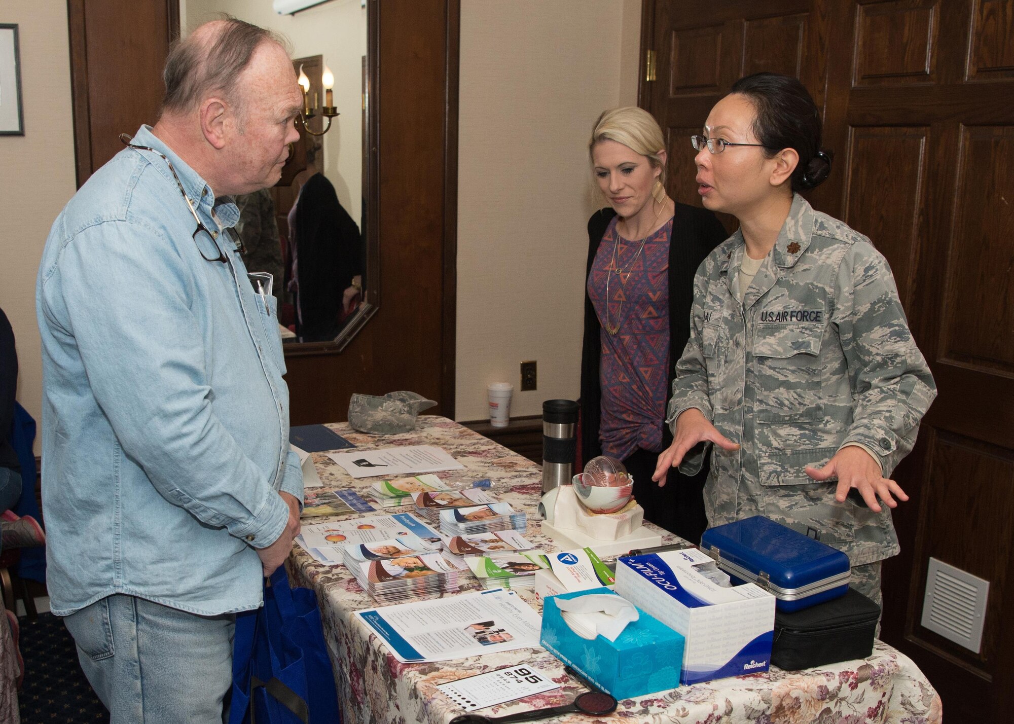 Maj. Marilyn Lai, 66th Medical Squadron optometrist, talks with Douglas Miller during Military Retiree Appreciation Day at the Minuteman Commons April 21, while Abigail Tarbox, 66 MDS optometry technician, listens. This year's event began with an Information Services session followed by a presentation by the Fraud Watch Network. (U.S. Air Force photo by Jerry Saslav)