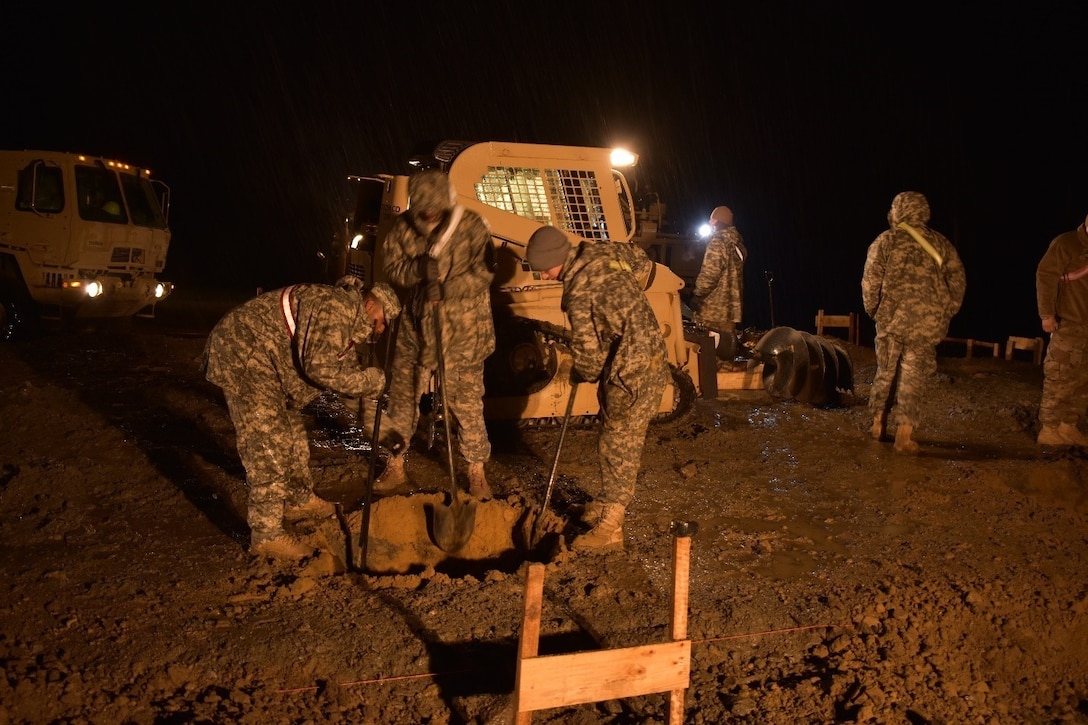 Soldiers of 1223rd Engineer Company, 778th Engineer Battalion, South Carolina Army National Guard, dig 36”x36”x36” post holes for the Multi-Purpose Covered Shelter at Cincu Training Area, Romania, on 19 April 2017. This exercise tested their proficiency in night-time engineering operations. The project is a part of Resolute Castle 17, an exercise which strengthens the NATO alliance and enhances its capacity to quickly respond to threats within the region. (US Army photo by Capt. Colin J. Cutler, 926th Engineer Brigade)