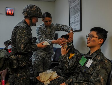 U.S. Air Force Maj. Anna Fedotova, 8th Medical Operation Squadron mental health flight chief, and a Republic of Korea Air Force (ROKAF) medical airman work together to bandage a ROKAF airman’s head during a mass casualty (MASCAL) exercise at Kunsan Air Base, Republic of Korea, April 19, 2017. The combined training gave first responders valuable experience and helped strengthen the relationship between U.S. and ROKAF medical units. 