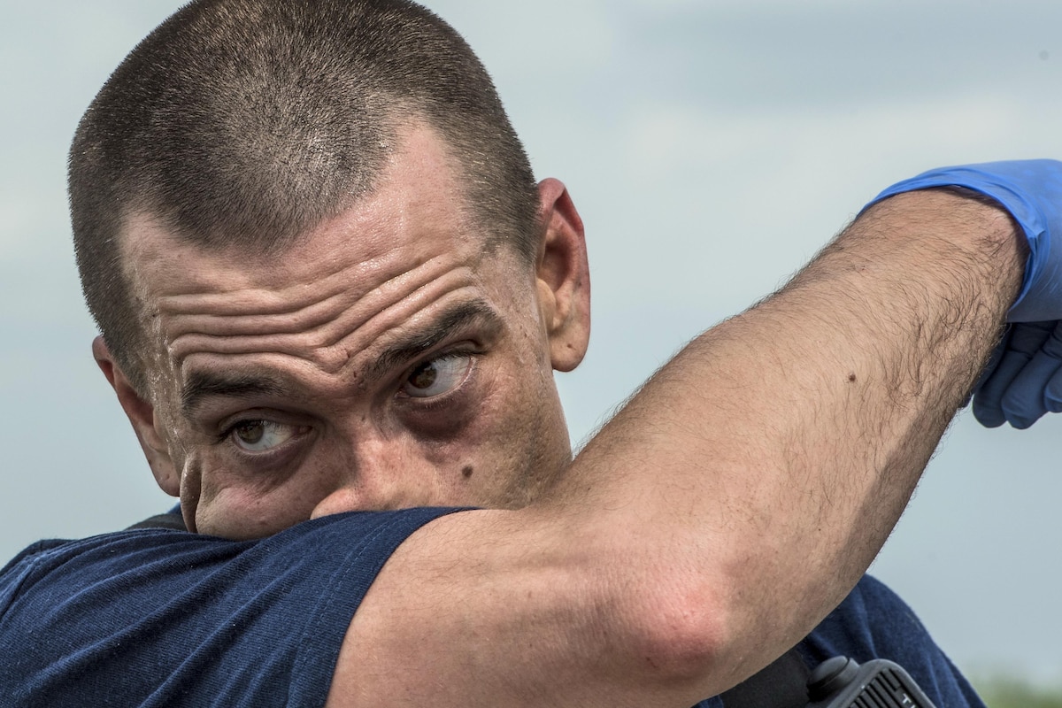 An airman wipes sweat from his face after tending to simulated injured patients.