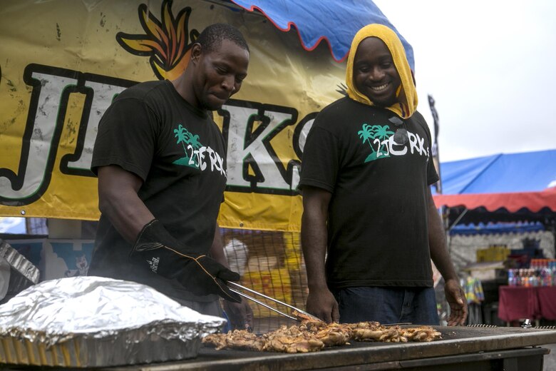 CAMP FOSTER, OKINAWA, Japan – Retired Staff Sgt. Fredrick I. Simpson, left, and Jamie Gibson grill outside of their 2 Jerks tent April 23 at the Camp Foster Festival in Okinawa, Japan. Simpson found his love for sharing Jamaican food through the Marine Corps Community Service Festivals. Gibson is Simpson’s high school best friend and business partner. (U.S Marine photo by Lance Corporal Tayler P. Schwamb)