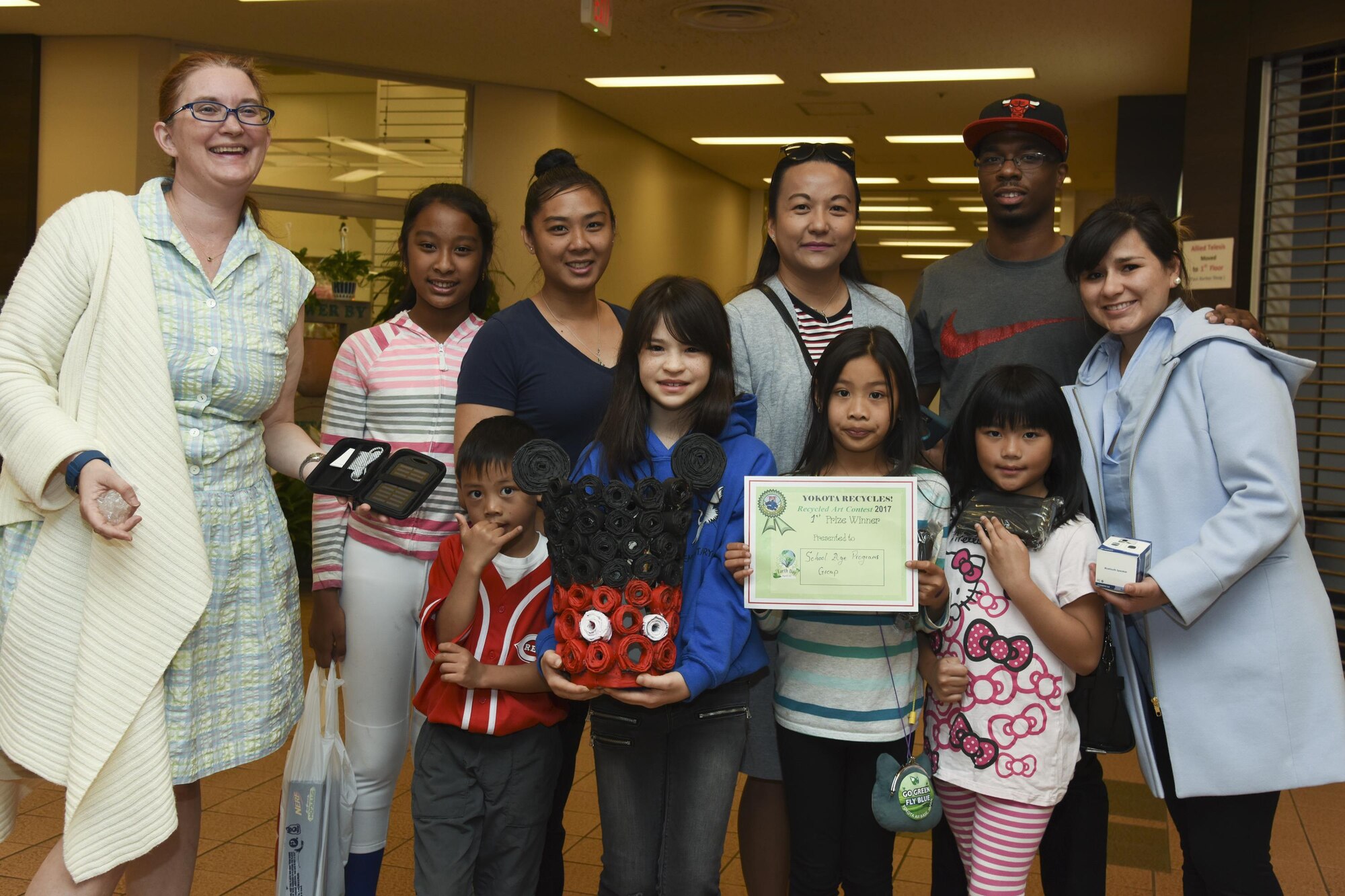 The first place winners in the group category of the Recycled Art Contest pose for a photo with teachers and event organizer April 22, 2017, at Yokota Air Base, Japan. The contest was hosted by the 374th Civil Engineer Squadron as part of the Earth Day eco-friendly activities and awarded the first place winners with a solar charger. (U.S. Air Force photo by Machiko Arita)
