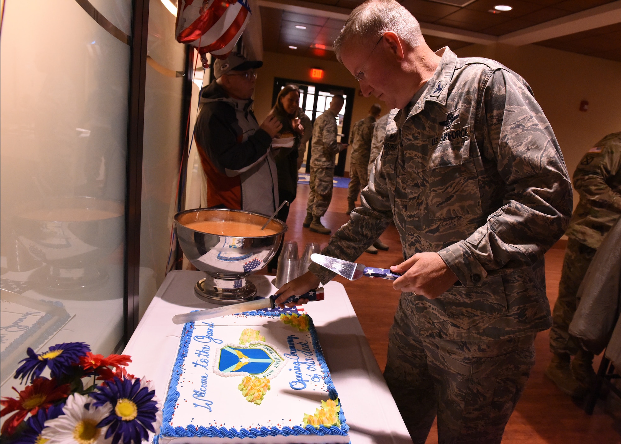 Col. Jeff Van Dootingh, commander of the 911th Airlift Wing, cuts the first slices of cake at a ribbon cutting ceremony at the Community Access Center, April 7, 2017. The ceremony was held to commemorate the opening of a new deck at the CAC which will allow 911th AW members to eat and socialize outside. (U.S. Air Force photo by Tech. Sgt. Jon Hehnly)