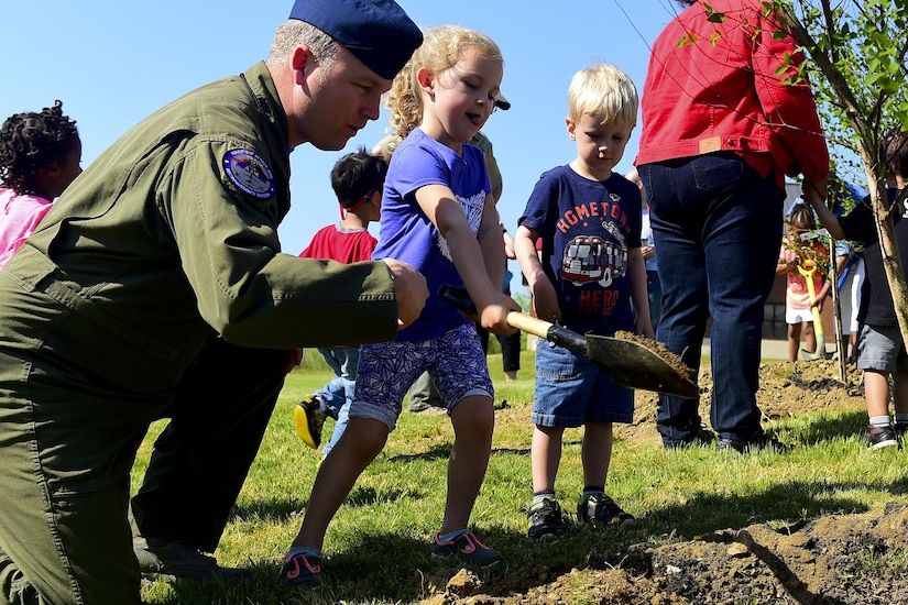 U.S. Air Force Master Sgt. Neal Scheuneman, Air Combat Command MQ-9 program manager, watches as his daughter, Charli Scheuneman, age 5, plants a tree during an Arbor Day event at Joint Base Langley-Eustis, Va., April 21, 2017. The trees were planted to help absorb carbon dioxide, which removes and stores the carbon while releasing the oxygen back into the air. (U.S. Air Force photo/Senior Airman Derek Seifert)