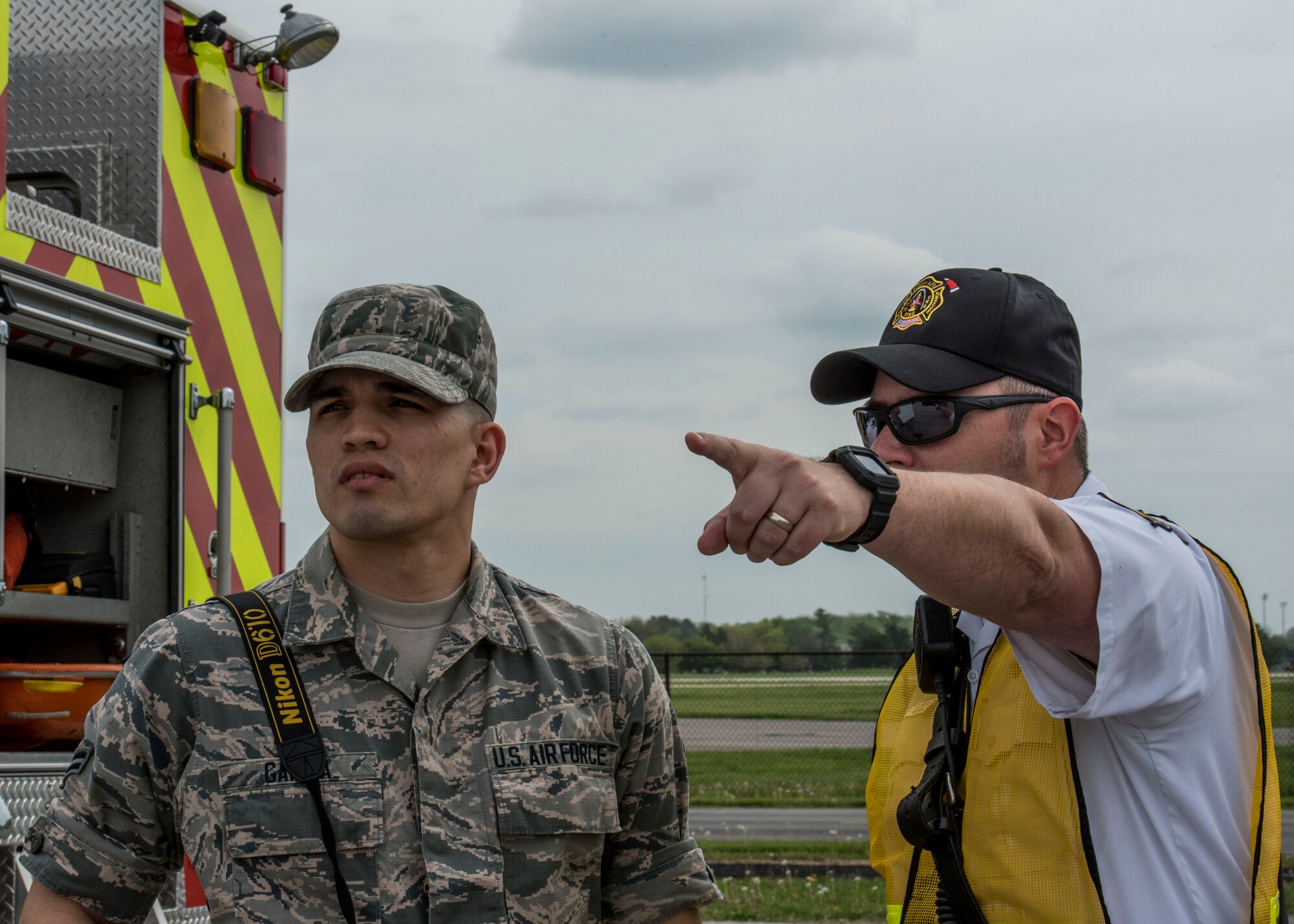 Airman 1st Class Daniel Garcia, 375th Air Mobility Wing Public Affairs, takes direction from Eric Belland, 375th Civil Engineer Squadron firefighter, on alert photography requirements during an exercise measuring the response of Scott personnel during an air show emergency, Scott Air Force Base, Ill., April 20, 2017.