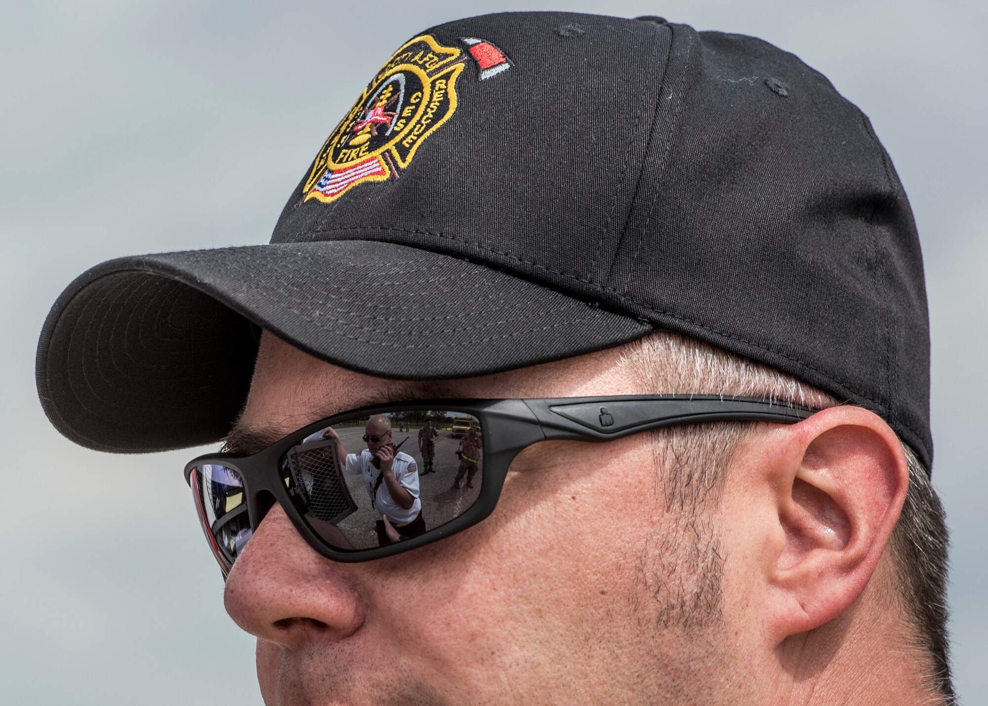 Timmy Lillie, 375th Civil Engineering Squadron firefighter, makes a radio call while reflecting in the sunglasses of Eric Belland, the incident commander during an exercise, Scott Air Force Base, Ill., April 20, 2017.  The exercise prepared Scott Air Force Base personnel for air show incident response.  First responders managed over 70 patients and practiced their procedures in the event of an aircraft accident.   (U.S. Air Force photo by Staff Sgt. Jodi Martinez)