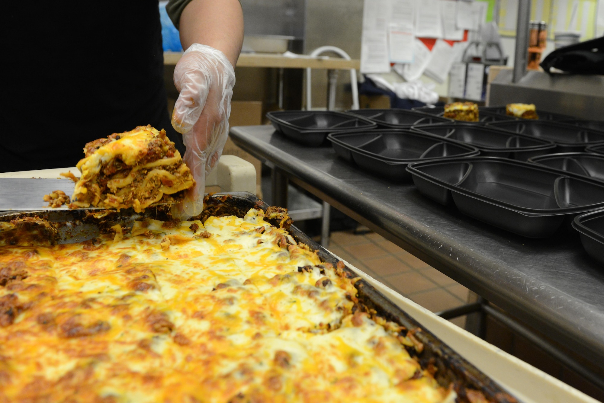 Rodel Magno, 673d Force Support Squadron Iditarod Dining Facility cook, serves lasagna in to-go containers for the Provisions on Demand at Joint Base Elmendorf-Richardson, Alaska, April 25, 2017. The DFAC prepares breakfast, lunch and dinner for the POD every Monday through Friday and Unit Training Assembly weekends.