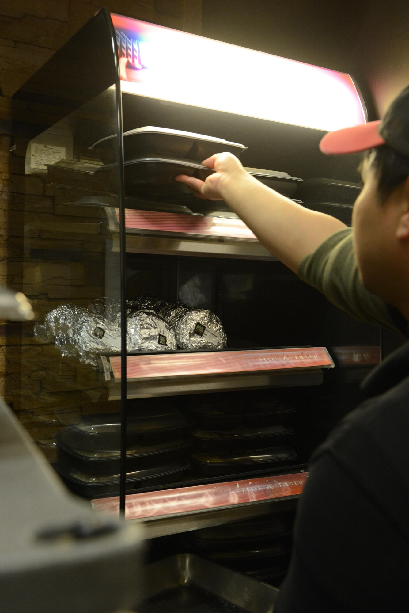 Rodel Magno, 673d Force Support Squadron Iditarod Dining Facility cook, places hot meals under heat lamps at the Provisions on Demand at Joint Base Elmendorf-Richardson, Alaska, April 25, 2017. The meals are in to-go containers because the POD’s primary customers are flightline personnel who do not have a lot of time and need hot meals.