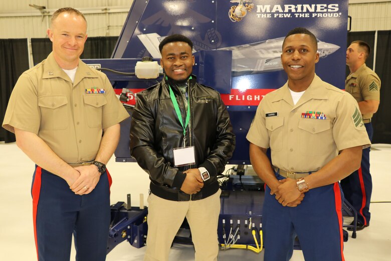 Marine Corps Sgt. Ramon Harris and Capt. Christopher Cory with 9 Marine Corps District, pose with a student next to the Marine Corps F-35 flight simulator during the 36 Annual Aerospace Conference and Career Fair at the University of North Dakota, April 20, 2017. According to the university’s website, SAMA invites prominent individuals from across the nation and from a variety of disciplines to join the students on campus and share their invaluable perspectives. (U.S. Marine Corps photo by Sgt. Jennifer Webster/Released)