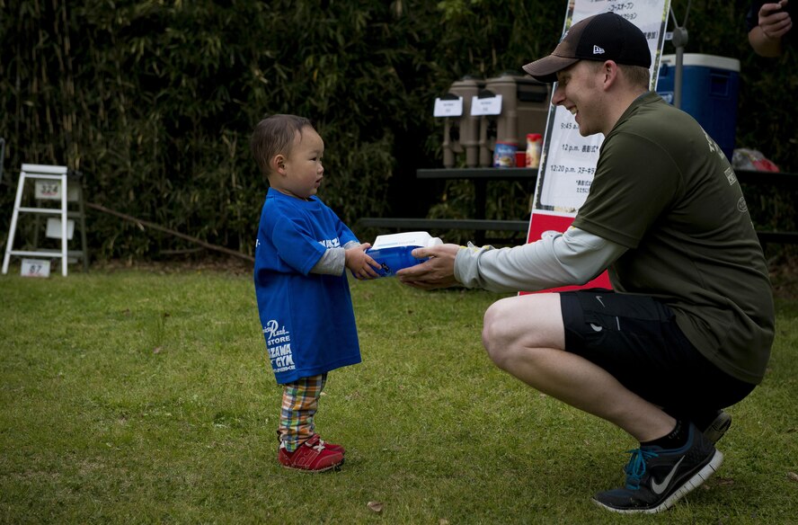 A volunteer hands a raffle prize to a child after the Tour de Tama mountain bike race April 22, 2017, at Tama Hills Recreation Area, Japan. After the race prizes were raffled off and lunch was provided for the participants and their families. (U.S. Air Force photo by Airman 1st Class Donald Hudson)