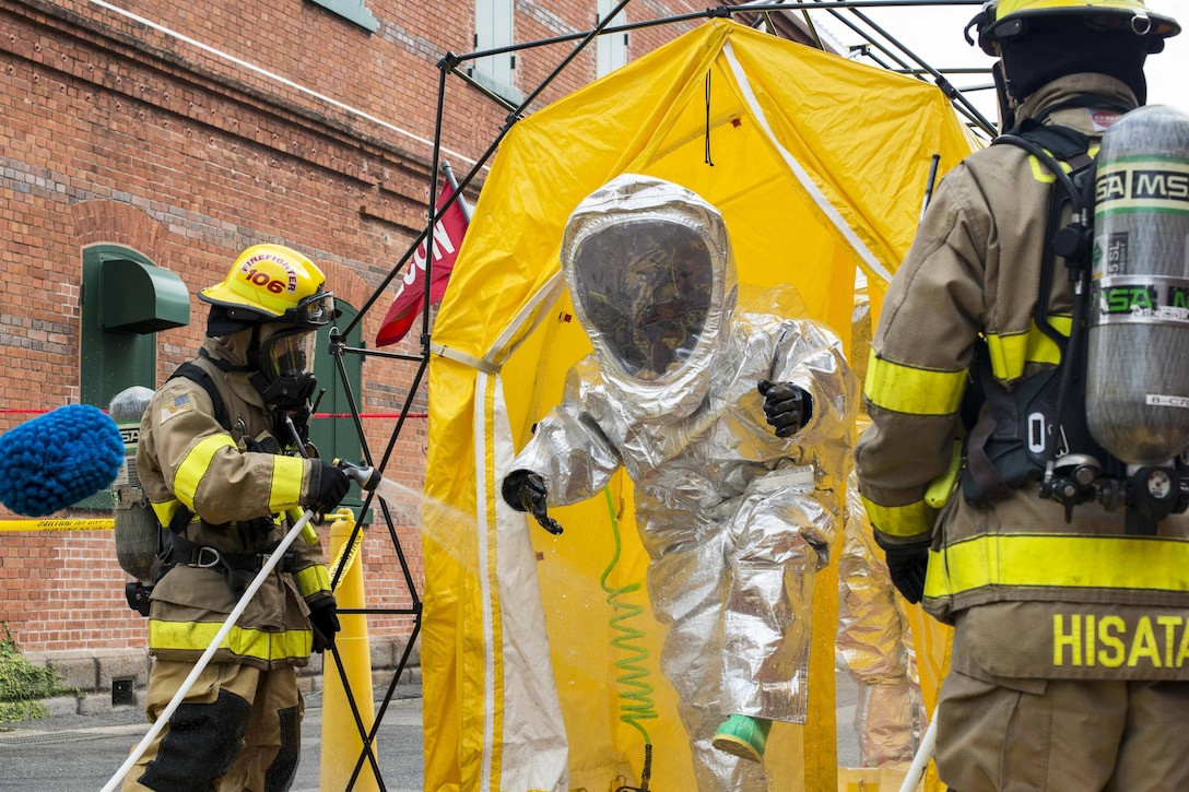 Sailors decontaminate a fire proximity suit during Exercise Reliant Gale at Commander, U.S. Fleet Activities Sasebo, Japan, April 18, 2017. The exercise trains naval installations in emergency preparedness and personnel accountability, evacuation and recovery operations from a catastrophic natural disaster. The sailors are assigned to Commander Naval Forces Japan Fire and Emergency Services. Navy photo by Seaman Geoffrey P. Barham