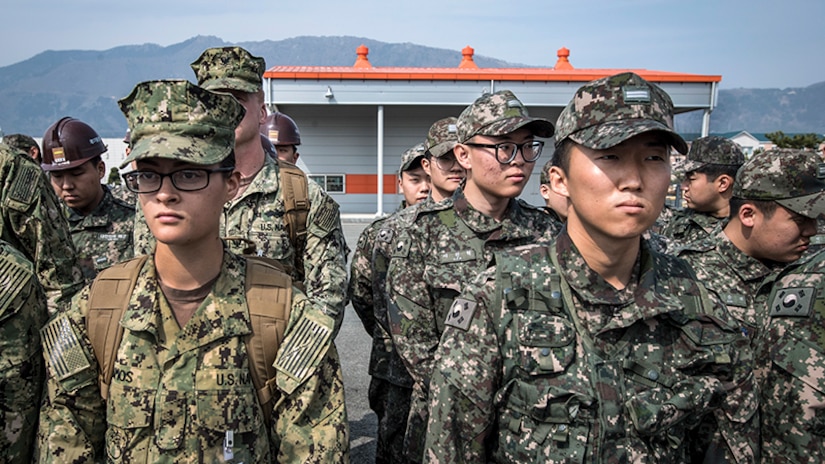 South Korean and U.S. sailors stand side by side listening.