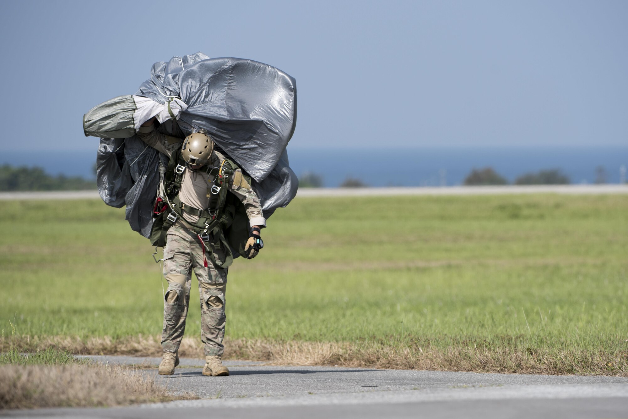 A U.S. Air Force Airman carries parachute gear after conducting a high altitude, low opening jump April 24, 2017, at Kadena Air Base, Japan. Soldiers and Airmen rely on properly prepared parachutes to safely land and conduct operations. (U.S. Air Force photo by Senior Airman Omari Bernard)