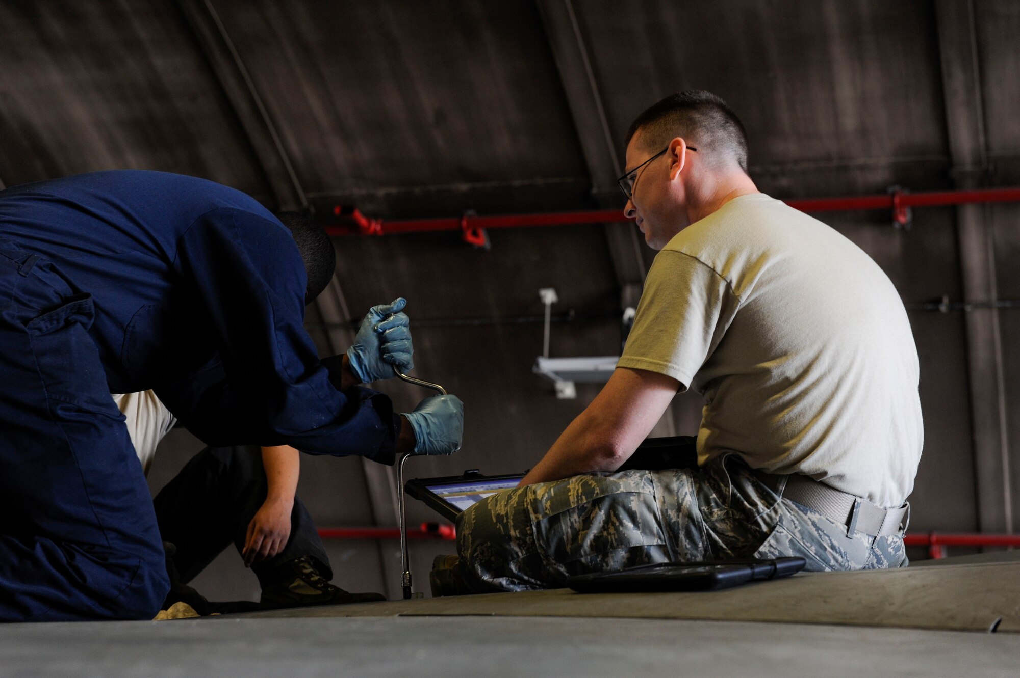 U.S. Air Force Airman 1st Class Tychaun Kingston, 44th Aircraft Maintenance Unit crew chief, unscrews a panel on an F-15 Eagle as Tech. Sgt. Timothy Peppler, 372nd Training Squadron, Detachment 15, F-15 aircraft maintenance instructor, supervises April 24, 2017, at Kadena Air Base, Japan. Aircraft maintenance instructors assigned to the 372nd TRS, Det. 15, assist with providing over 2,000 hours of instruction to Airmen. (U.S. Air Force photo by Senior Airman Lynette M. Rolen)