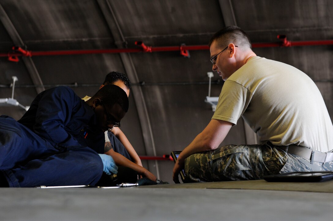 U.S. Air Force Airman 1st Class Tychaun Kingston, 44th Aircraft Maintenance Unit crew chief, performs maintenance on an aileron switching valve as Tech. Sgt. Timothy Peeler, 372nd Training Squadron, Detachment 15, F-15 Eagle aircraft maintenance instructor, observes April 24, 2017, at Kadena Air Base, Japan. The aileron switching valve is one of the hydraulic systems on the F-15 Eagle. (U.S. Air Force photo by Senior Airman Lynette M. Rolen)