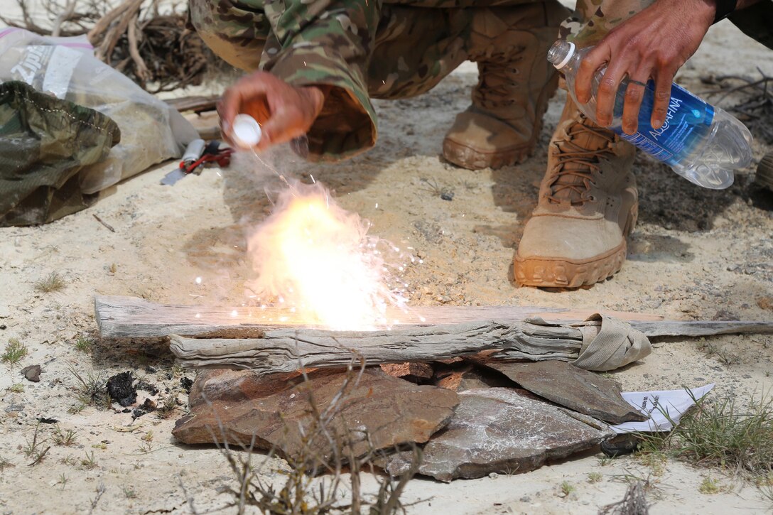 Air Force Tech. Sgt. Isaac Houston starts a fire by using a meal, ready to eat heater and a cap of water during survival, evasion, resistance and escape training at the Yakima Training Center, Yakima, Wash., April 25, 2017. Army photo by Sgt. Kalie Jones