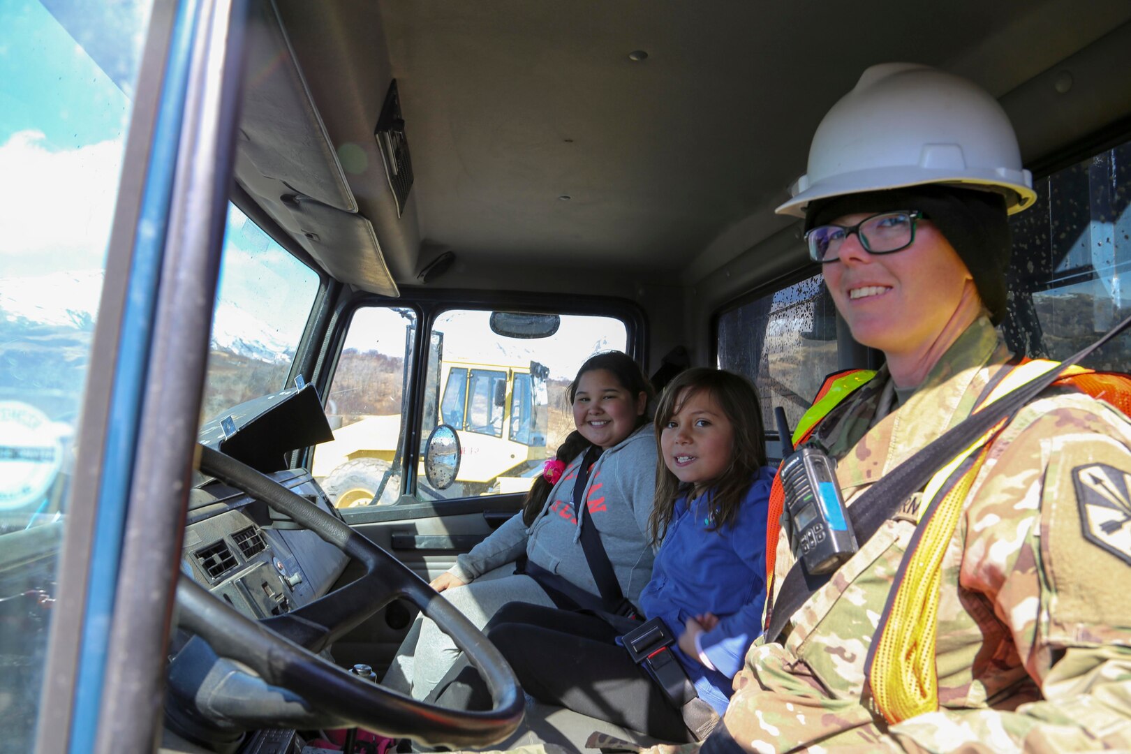 Pfc. Amanda Schmidling, a horizontal construction engineer with the Arizona National Guard’s 259th Engineer Platoon, drives local school students around during their visit to the Innovative Readiness Training runway extension project at Old Harbor, Alaska, April 20, 2017. 