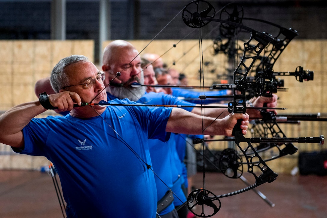 Mike Morales and a row of Warrior CARE athletes draw back their bows during an adaptive sports camp at Eglin Air Force Base, Fla., April 26, 2017. Air Force photo by Samuel King Jr.
