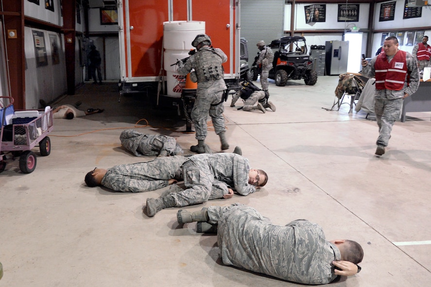 Airmen playing the role of hostages lay on the floor at building 732, Hill Air Force Base, while 75th Security Forces Squadron Airmen neutralize an Airman playing the role of an active shooter. Wing Inspection Team members in red vests look during the response exercise April 24. (U.S. Air Force/Todd Cromar)
