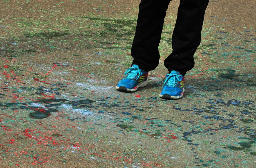 A volunteer waits on the color-splattered road during the Minot Meltdown color run at Minot Air Force Base, N.D., April 25, 2017. There were six different color stations throughout the course. (U.S. Air Force photo/Senior Airman Apryl Hall)