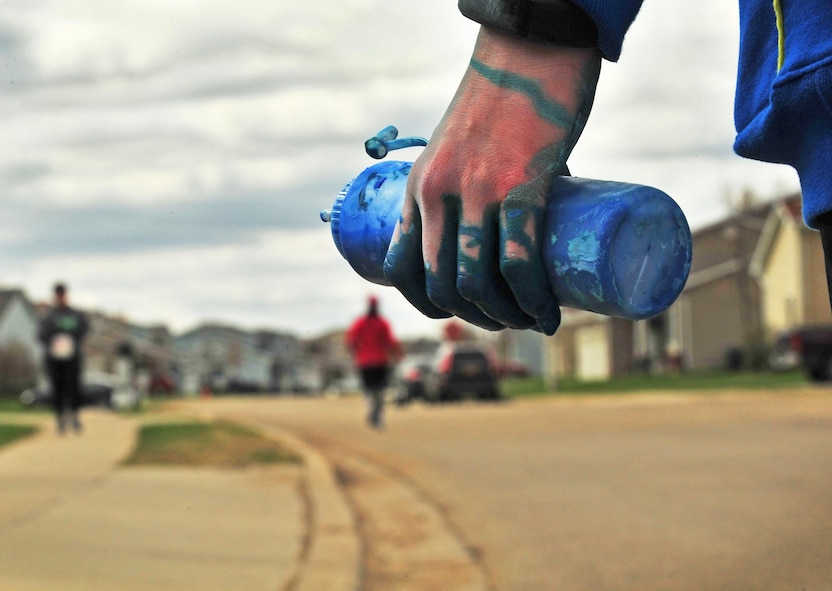 A volunteer waits to spray oncoming runners with color during the Minot Meltdown color run at Minot Air Force Base, N.D., April 25, 2017. The fourth annual run was hosted by the Health and Wellness Center, Alcohol and Drug Abuse Prevention, Family Advocacy Program and Sexual Assault Prevention and Response Program. (U.S. Air Force photo/Senior Airman Apryl Hall)