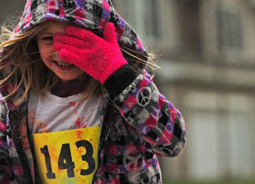 A young runner wipes her eyes during the Minot Meltdown color run at Minot Air Force Base, N.D., April 25, 2017. Runners had the option of running a 5K or 10K race. (U.S. Air Force photo/Senior Airman Apryl Hall)