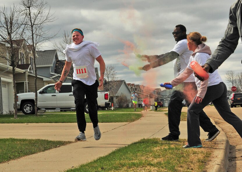 Volunteers throw color on a runner during the Minot Meltdown color run at Minot Air Force Base, N.D., April 25, 2017. There were six color stations throughout the race route. (U.S. Air Force photo/Senior Airman Apryl Hall)