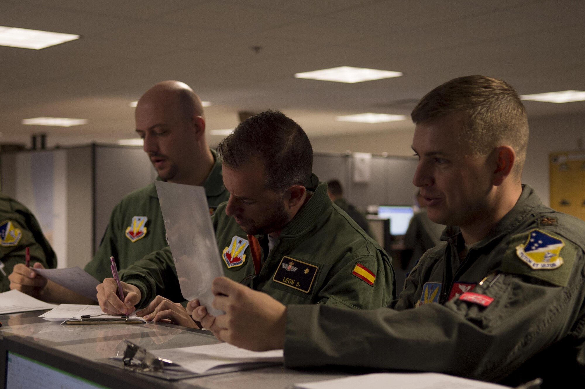 Maj. Aaron, a 29th Attack Squadron MQ-9 Reaper instructor pilot, right, Maj. Jaime, a Spanish air force student pilot, middle, and Staff Sgt. Francisco, a Spanish air force student sensor operator, left, review MQ-9 information at the step desk prior to a flight, at Holloman Air Force Base, N.M. on April 5, 2017. Spain is currently participating in essential training here at the MQ-9 formal training unit. (U.S. Air Force photo by Tech. Sgt. Amanda Junk)