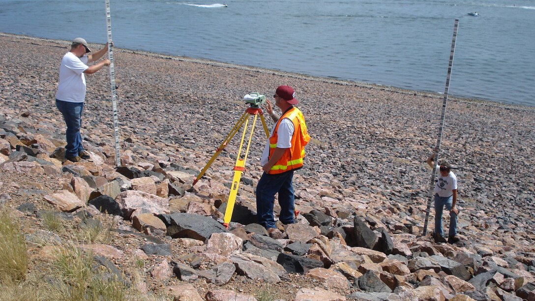 Field surveyors Nick Michael, Dave Salter and Michael Swinford run a level loop to establish current year elevations for tiltmeters, sensitive inclinometers designed to measure small structure changes, at Cherry Creek Dam near Denver, Colorado.
