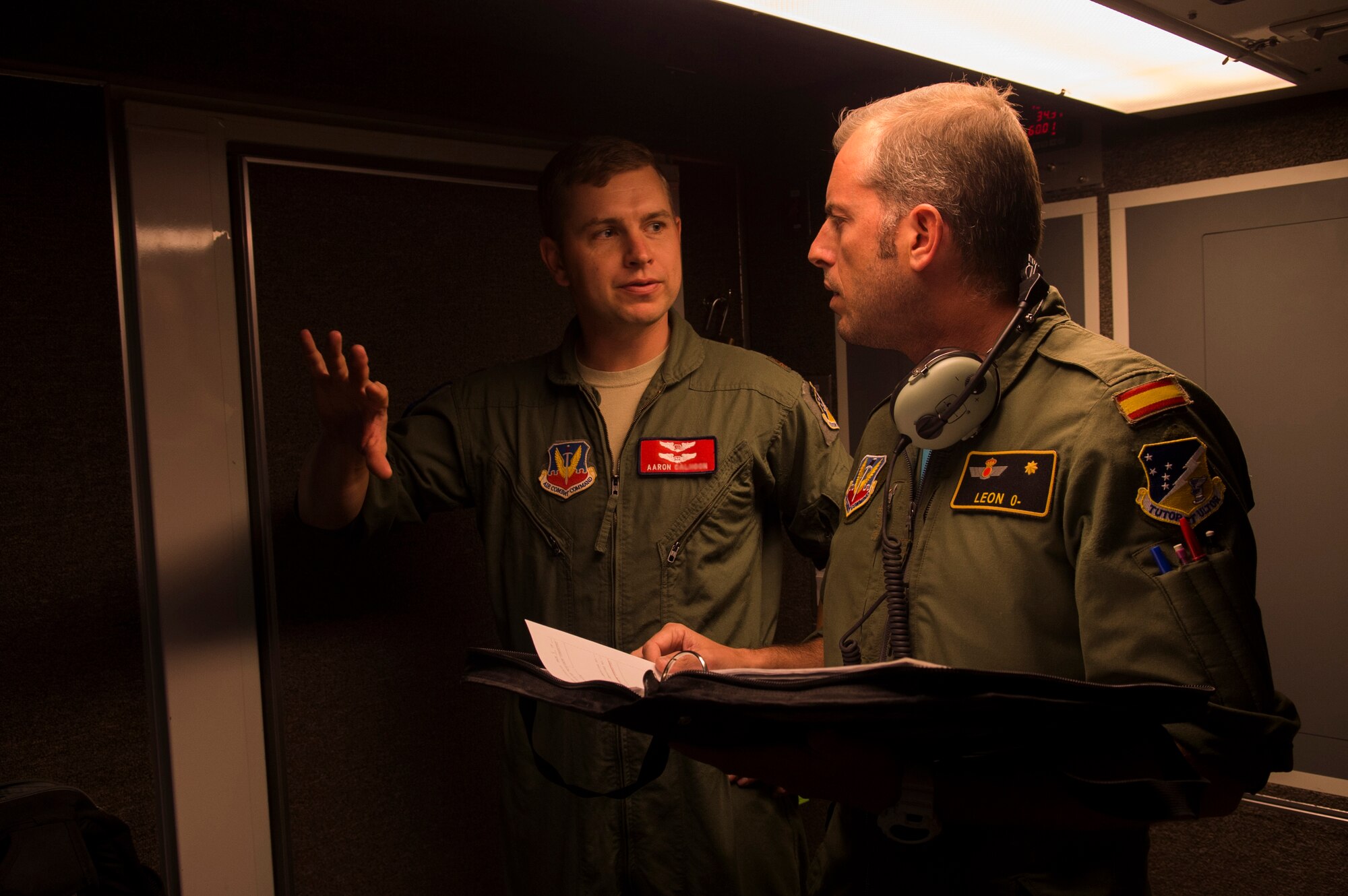 Maj. Aaron, a 29th Attack Squadron MQ-9 Reaper instructor pilot, left, and Maj. Jaime, a Spanish air force student pilot, right, discuss MQ-9 flight procedures at Holloman Air Force Base, NM on April 19, 2017. Spain is currently participating in essential training here at the MQ-9 formal training unit. (U.S. Air Force photo by Tech. Sgt. Amanda Junk)